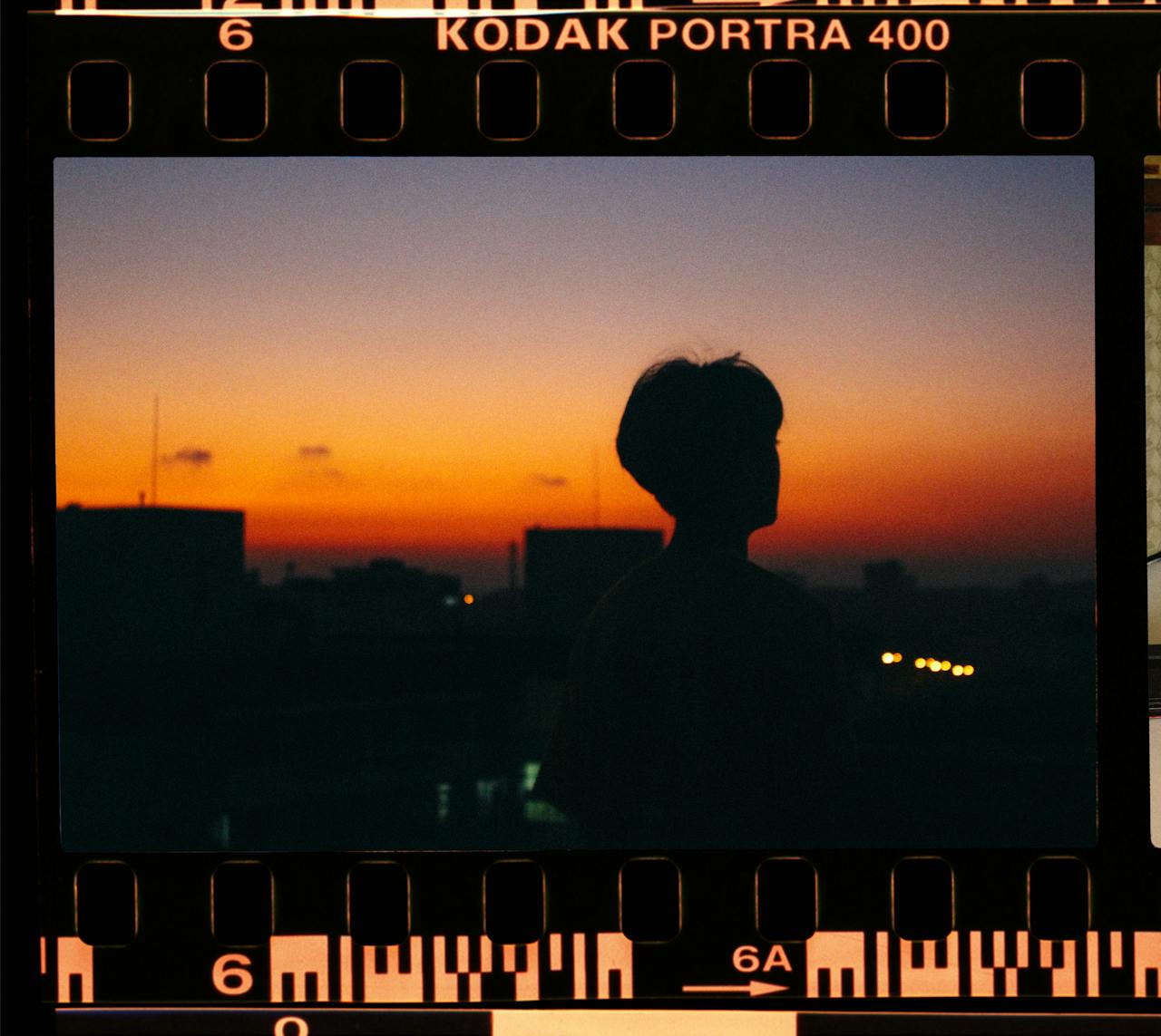 hero-img-01 Silhouette of a person against a vibrant sunset, captured on Kodak Portra 400 filmstrip.