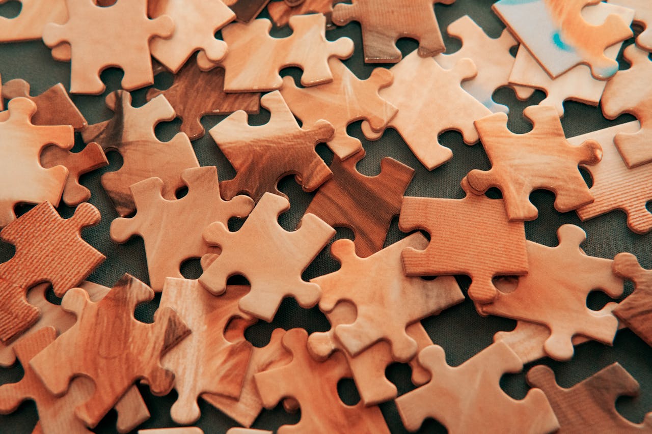 our-services-2 A close-up view of scattered wooden jigsaw puzzle pieces on a dark surface.